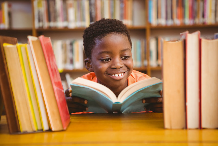 Cute little boy reading book in the library