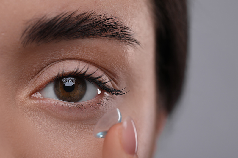 Closeup view of young woman putting in contact lens