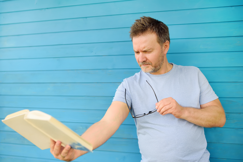 Man holding book at arm's length